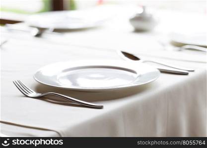 White plate with knife and fork on decorated table. White plate with knife and fork