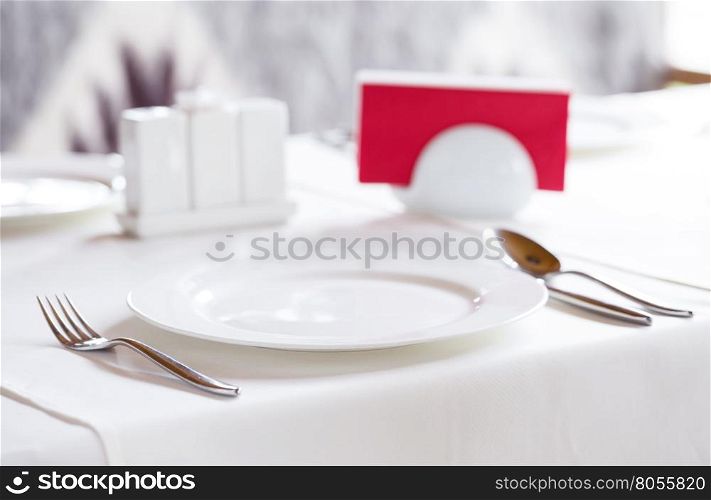 White plate with metal cutlery to serve a table. White plate with metal cutlery