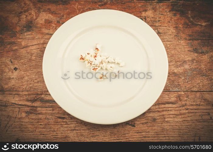 White plate with popcorn on wood table