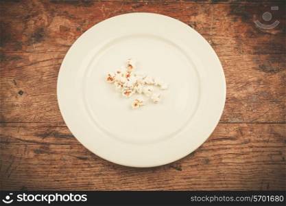 White plate with popcorn on wood table