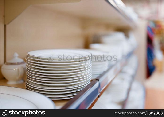 White plates on the shelf closeup, houseware store, nobody. Home goods in market, kitchenware supply shop products. White plates on the shelf closeup, houseware store