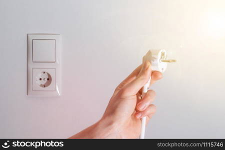 White plug with cable in males hand, ready to connect. Energy concept.