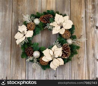 White Poinsettia flower and pine cone Christmas wreath on rustic cedar wood.