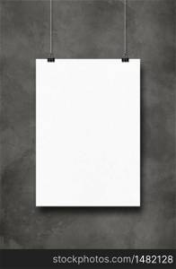 White poster hanging on a dark concrete wall with clips. Blank mockup template. White poster hanging on a dark concrete wall with clips