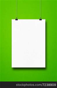 White poster hanging on a green wall with clips. Blank mockup template. White poster hanging on a green wall with clips
