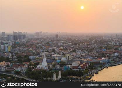 White Prayoon Pagoda, Memorial Bridge, and Phra Pok Klao Bridge with buildings and curve of Chao Phraya River at sunset. Urban city, Downtown Bangkok, Thailand.