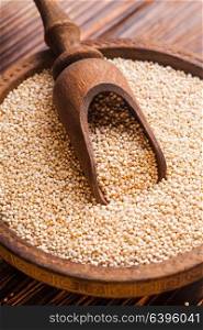 White quinoa seeds on a wooden spoons in a wooden bowl. Pile of quinoa grain