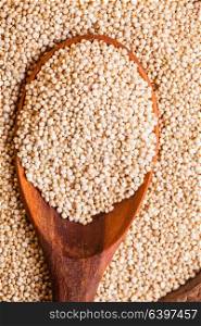 White quinoa seeds on a wooden spoons in a wooden bowl. Pile of quinoa grain