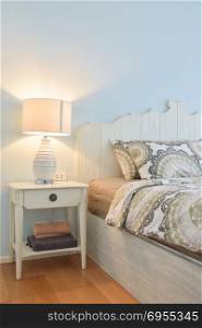 White reading lamp next to modern country style bedding