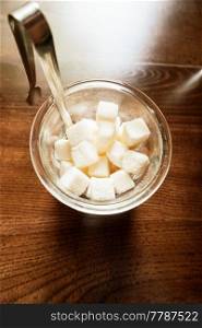 White Refined Sugar Cubes in the sugar-bowl top view on wooden background. Sugar in the bowl top view on wooden background
