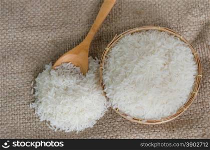 white rice grains on sackcloth. white rice grains with wooden spoon on sackcloth