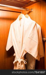 White robes with wooden hangers in hotel wardrobe