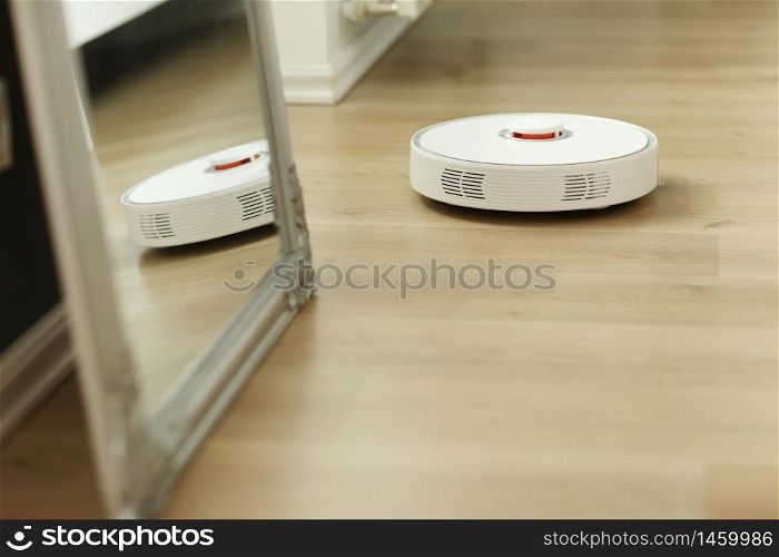 white robotic vacuum cleaner. The robot is controlled by voice commands for direct cleaning. Modern technology of smart cleaning. scheduled cleaning of the apartment. selective focus.. white robotic vacuum cleaner. The robot is controlled by voice commands for direct cleaning. Modern technology of smart cleaning. scheduled cleaning of the apartment. selective focus