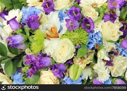 White roses and blue purple flowers in a wedding flower arrangement