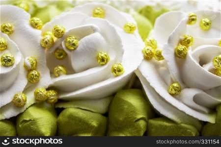 White roses and green leaves with yellow beads, made with cream, closeup.. White roses and green leaves made with cream, closeup.