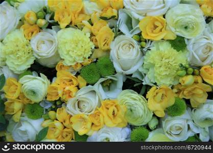 White roses, yellow freesia and carnations in a mixed floral composition