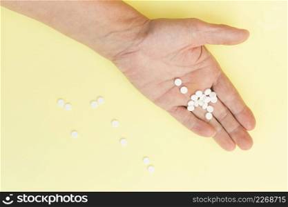 white round tablets hand person against yellow background