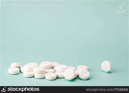 White round tablets scattered on colour background. Heap of white round pills close-up