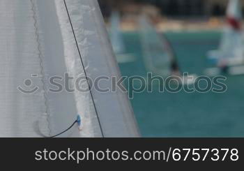 white sail waving on the wind in the background windsurfers