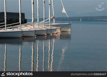 White Sailboats Anchored on Serene Sea, Boats Reflection in Water