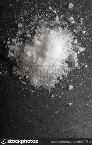 White salt crushed on dark stone background. Close-up Big pieces of salt. Heap pouder salt and natural light.