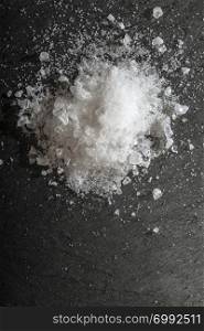 White salt crushed on dark stone background. Close-up Big pieces of salt. Heap pouder salt and natural light.
