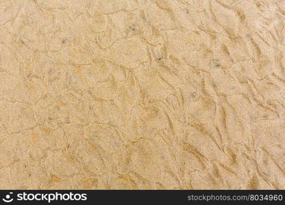 White sand background with barely visible waves after surf on beach.