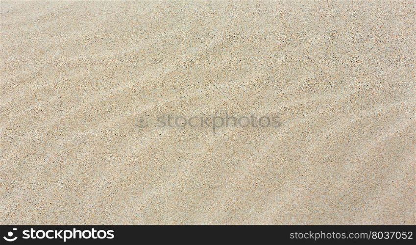 White sand background with barely visible waves after surf on beach.