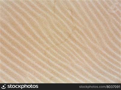 White sand background with barely visible waves after surf on beach.
