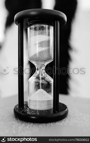 white sand hourglass in brown wood on table