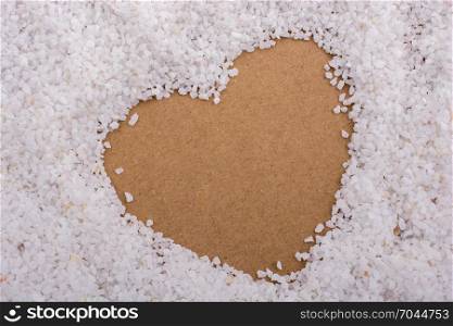 White sand stone form a heart shape on brown background