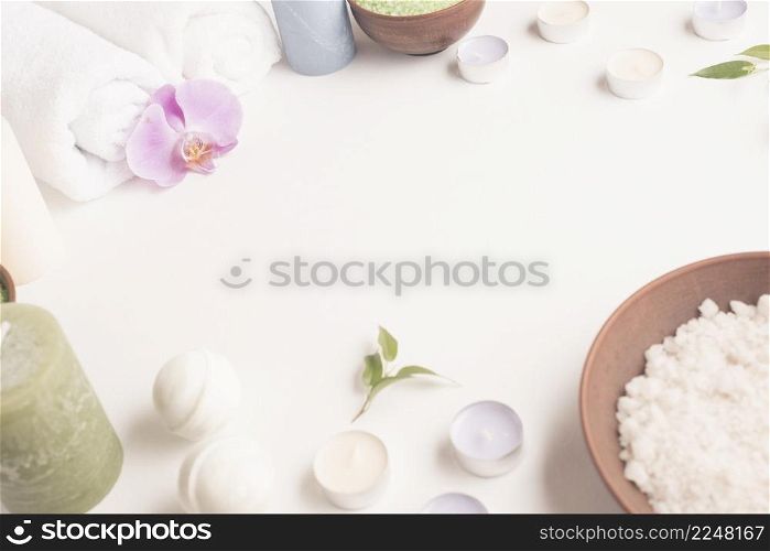 white sea salt candles rolled up towel spa bomb white background