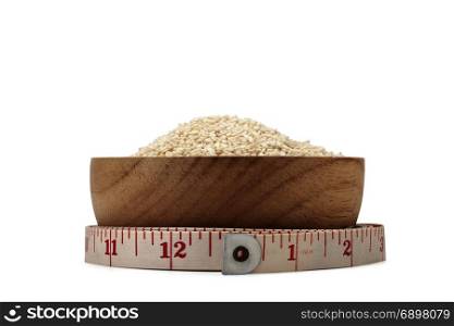 white sesame seeds in wooden bowl with measuring tape isolated on white background with clipping path