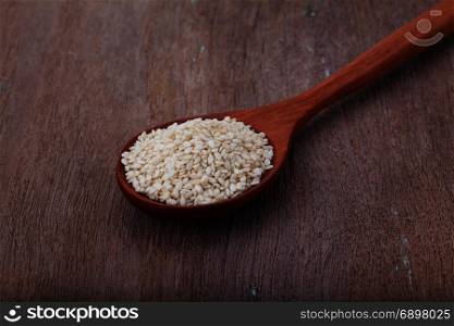 white sesame seeds in wooden spoon on wood background