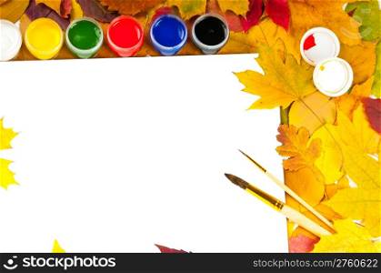 white sheet of paper with paints and brushes on the background of autumn leaves