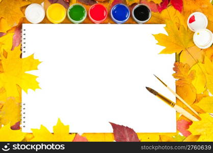 white sheet of paper with paints and brushes on the background of autumn leaves