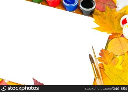 white sheet of paper with paints and brushes on the background of autumn leaves