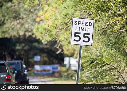"White sign with "speed limit 55" printed in black on country road"