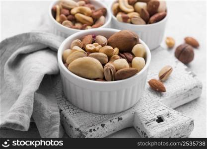 white small bowls filled with assortment nuts cutting board
