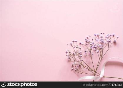 white small flowers, pink background, white ribbon, place for text, vertical. Pink tablet for text with a background of white flowers and ribbon