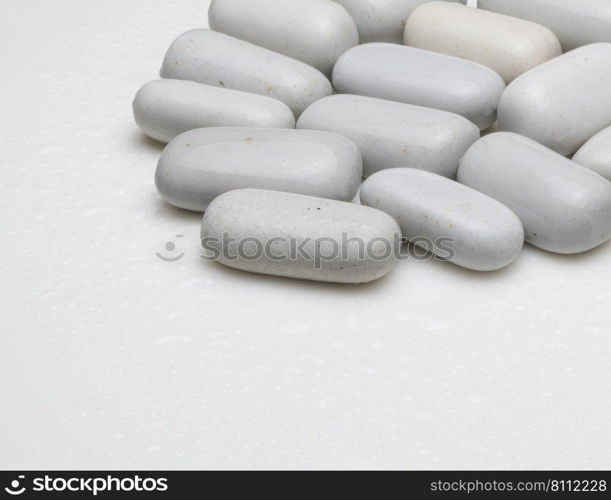 white smooth stones with water drops on light background. rounded white stones