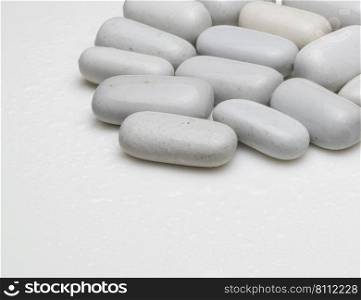 white smooth stones with water drops on light background. rounded white stones