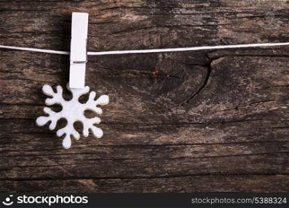 White snowflake decoration attached to the rope, over wooden background