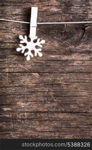 White snowflake decoration attached to the rope, over wooden background