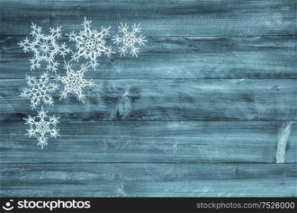White snowflakes on blue wood background. Winter holidays decoration
