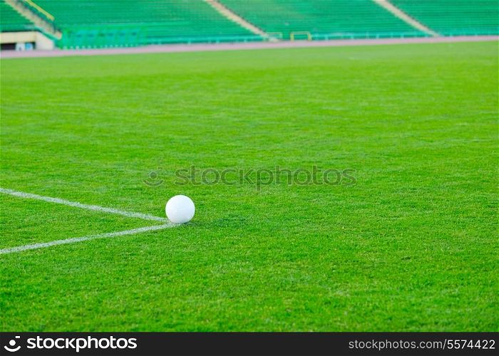 white Soccer ball on grass at goal and stadium in background