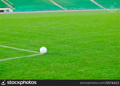 white Soccer ball on grass at goal and stadium in background