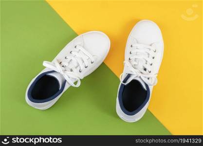 White sports shoes, sneakers with shoelaces on a green and yellow background. Sport lifestyle concept Top view Flat lay.. White sports shoes, sneakers with shoelaces on a green and yellow background. Sport lifestyle concept Top view Flat lay