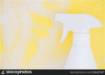 white spray bottle against soap sud yellow backdrop