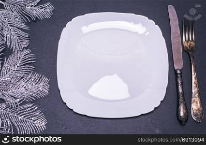 white square ceramic plate with cutlery and Christmas decorations